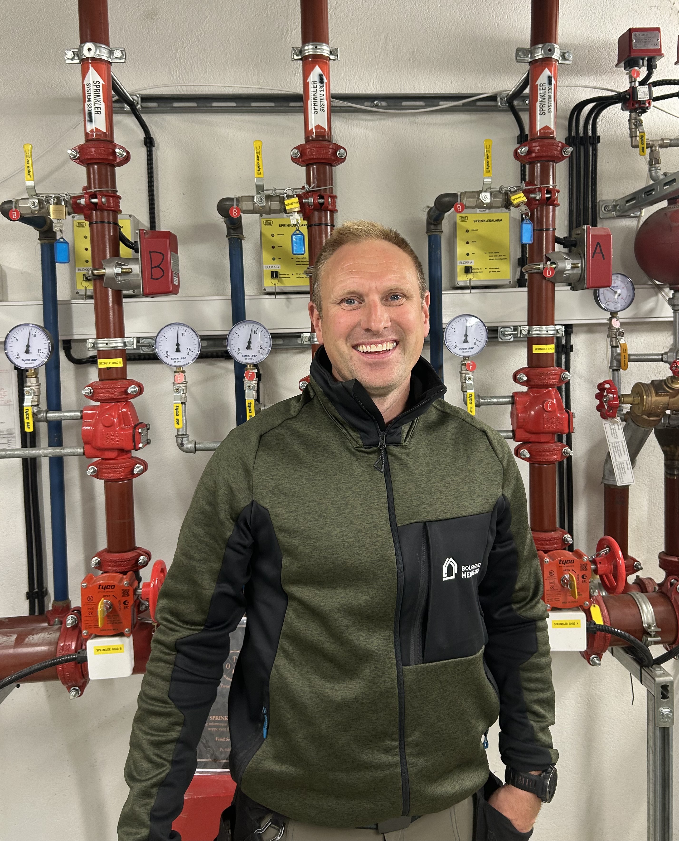 Driftstekniker fra Boligservice Helgeland foran sprinkleranlegg